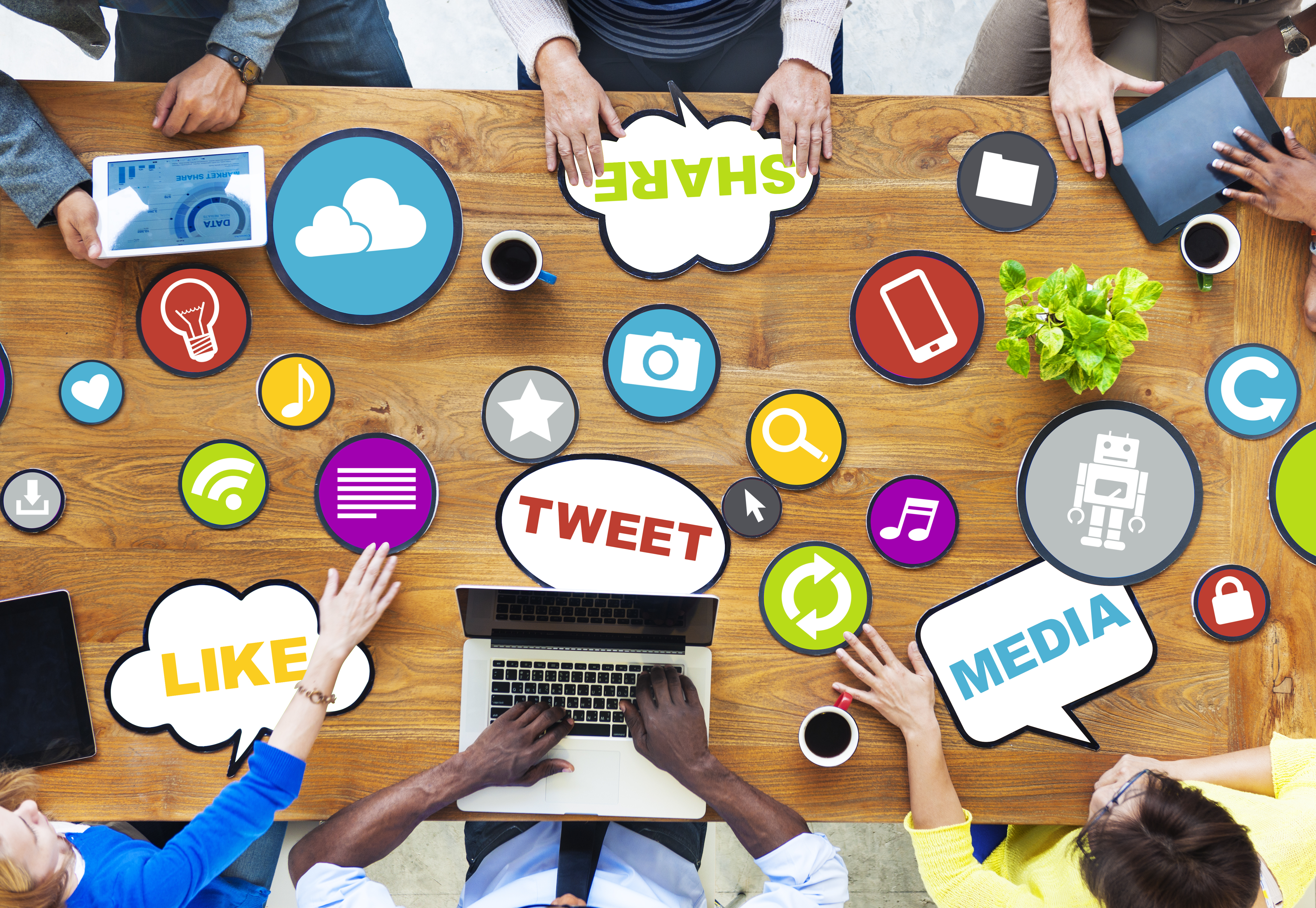 picture of table covered in social media logos with several people around table holding a meeting